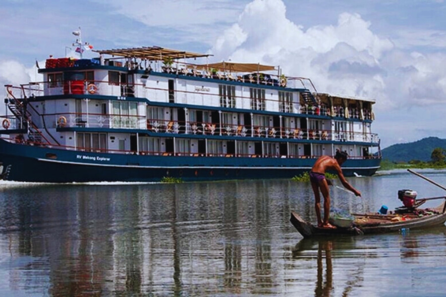 Local fisherman beside luxury Mekong River Cruise sailing through peaceful scenery